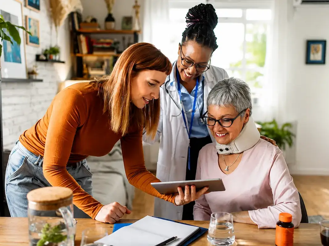 A caregiver reviewing plans with a family member and a senior woman at home